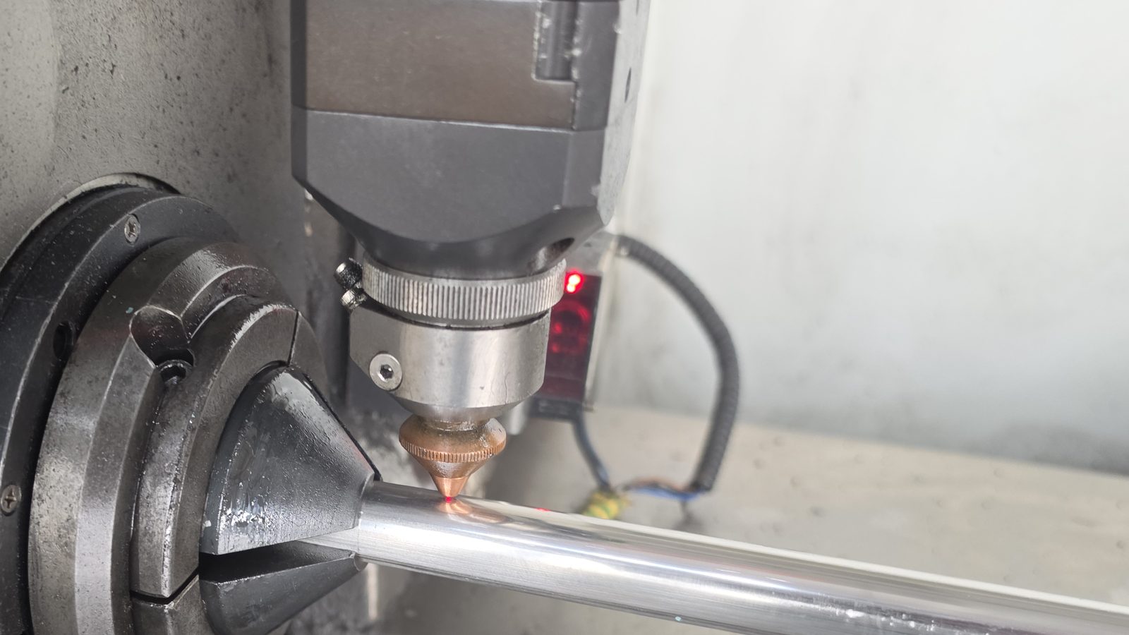 Laserkopf schneidet ein Edelstahlrohr, am Schnittpunkt glüht der Werkstoff