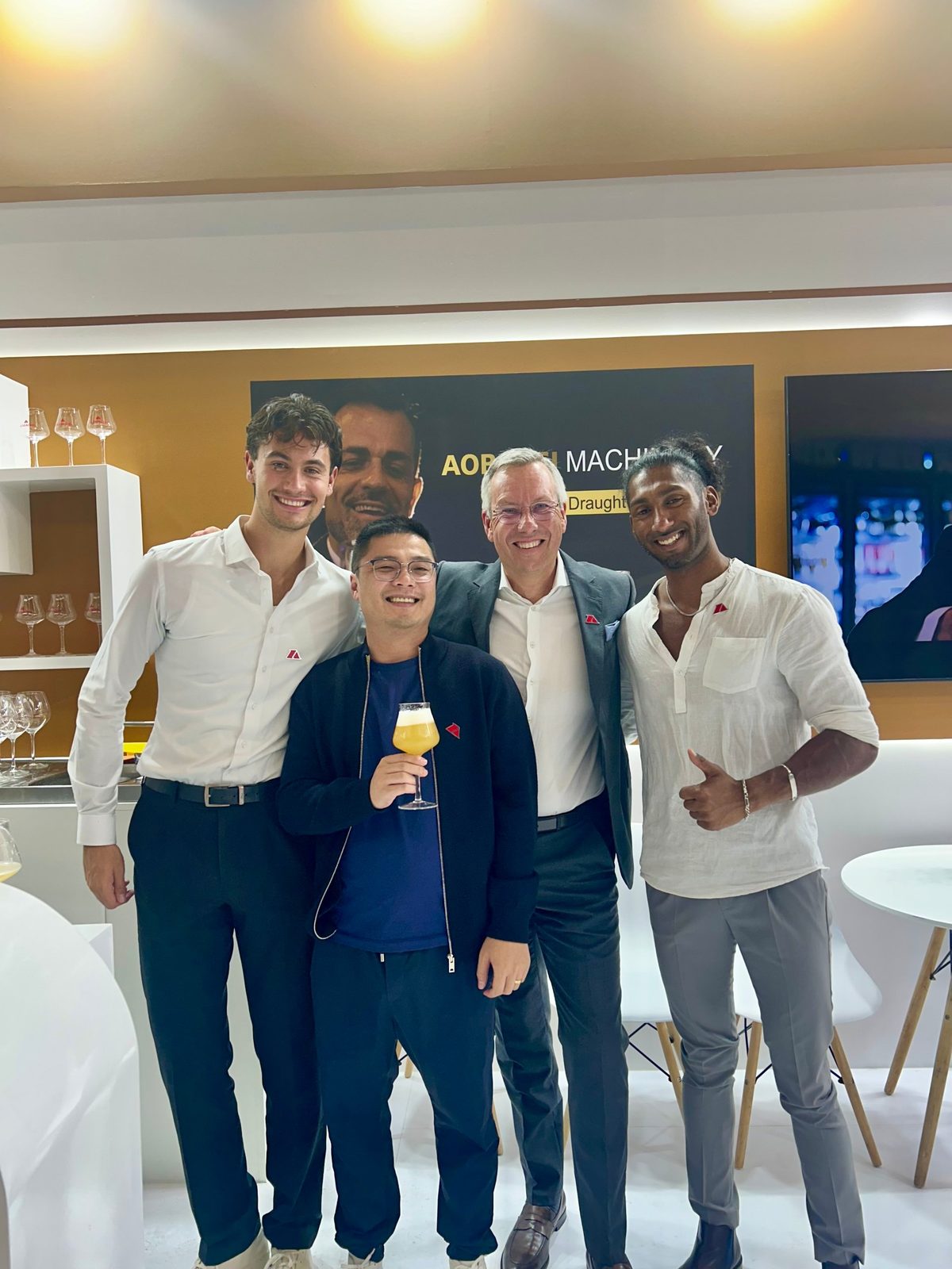 Four members of the AOBAOSI stand team with a glass of beer